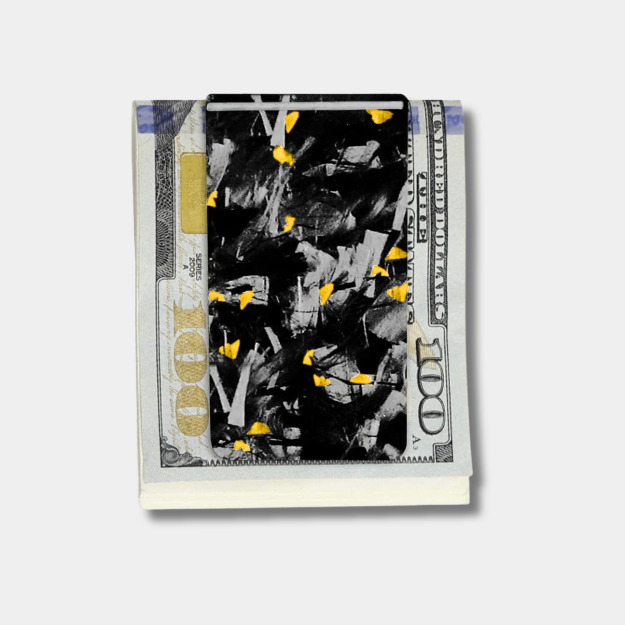 Forged Karbon™ money clip in black composite with gold accents holding bills by Karbon Technik.