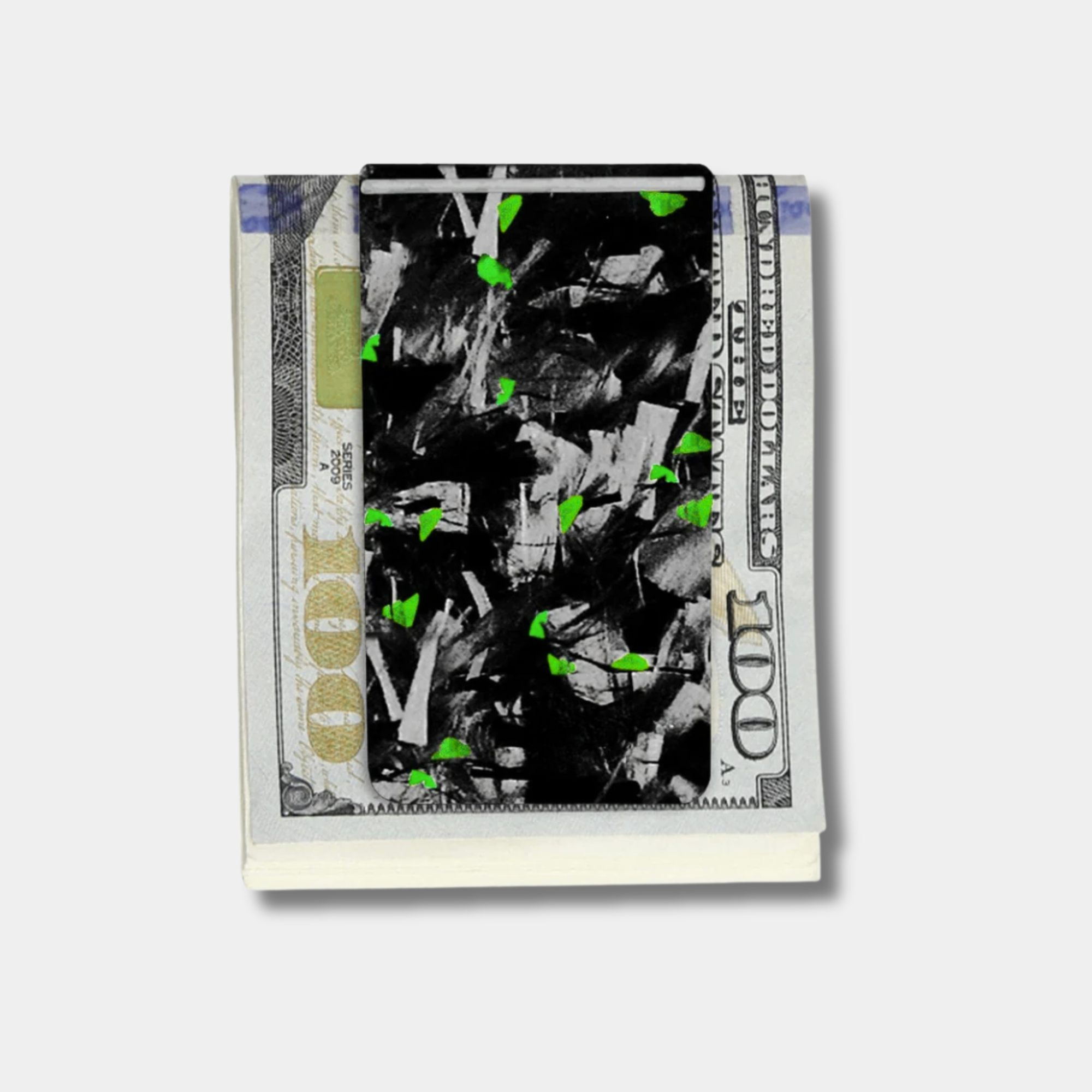 Forged Karbon™ money clip in black composite with green accents holding bills by Karbon Technik.