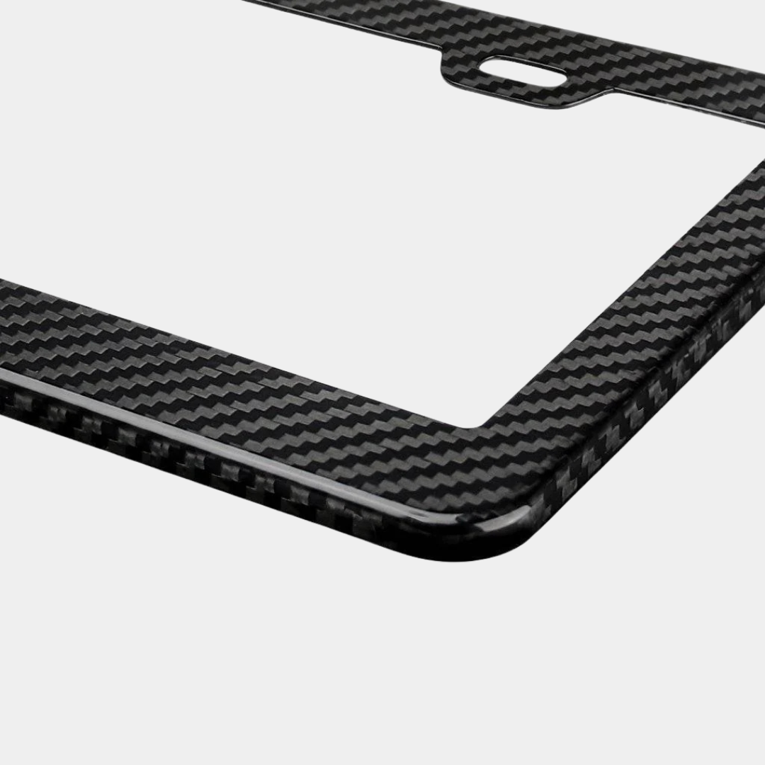 Close-up of Karbon Technik black woven carbon fibre car licence plate frame, showing weave detail and a mounting hole.